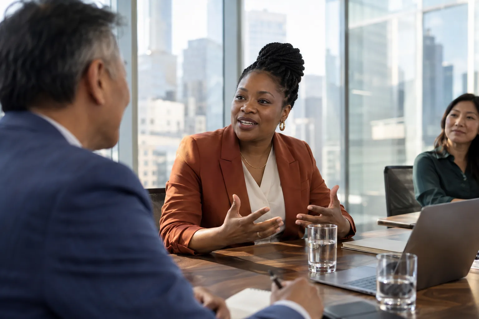 A rep speaks warmly with a client in a glass-walled meeting room
