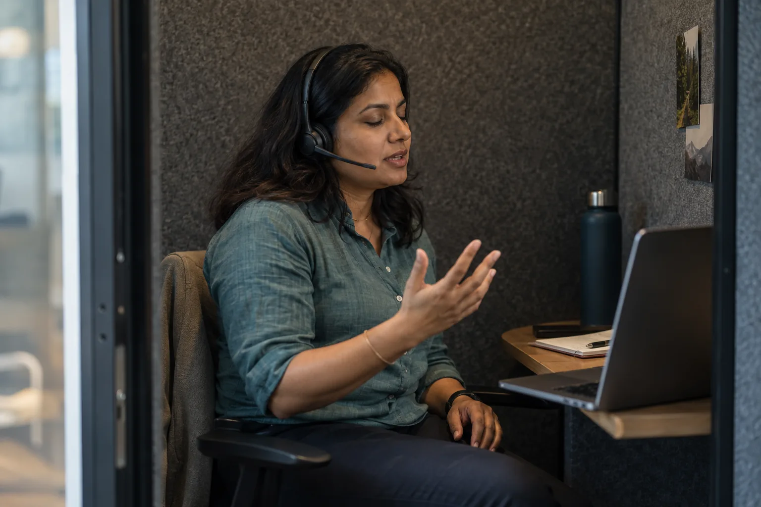 A rep practises a call with a headset in a small phone booth