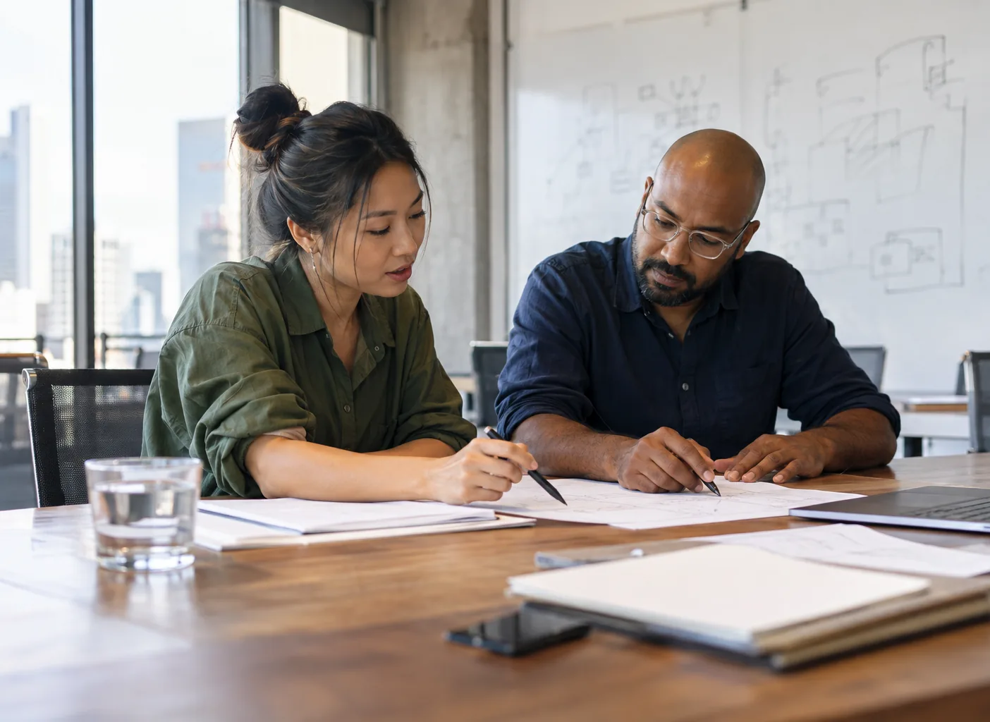 A founder takes the first salesperson through a plan at a long table